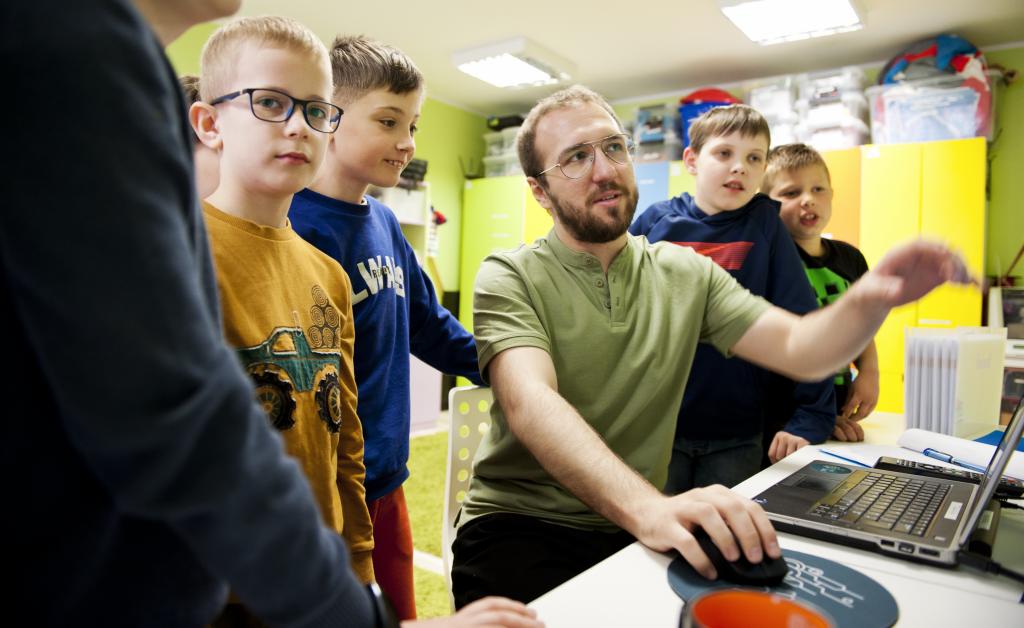 Damian pokazuje dzieciom zajecia na komputerze trenerskim